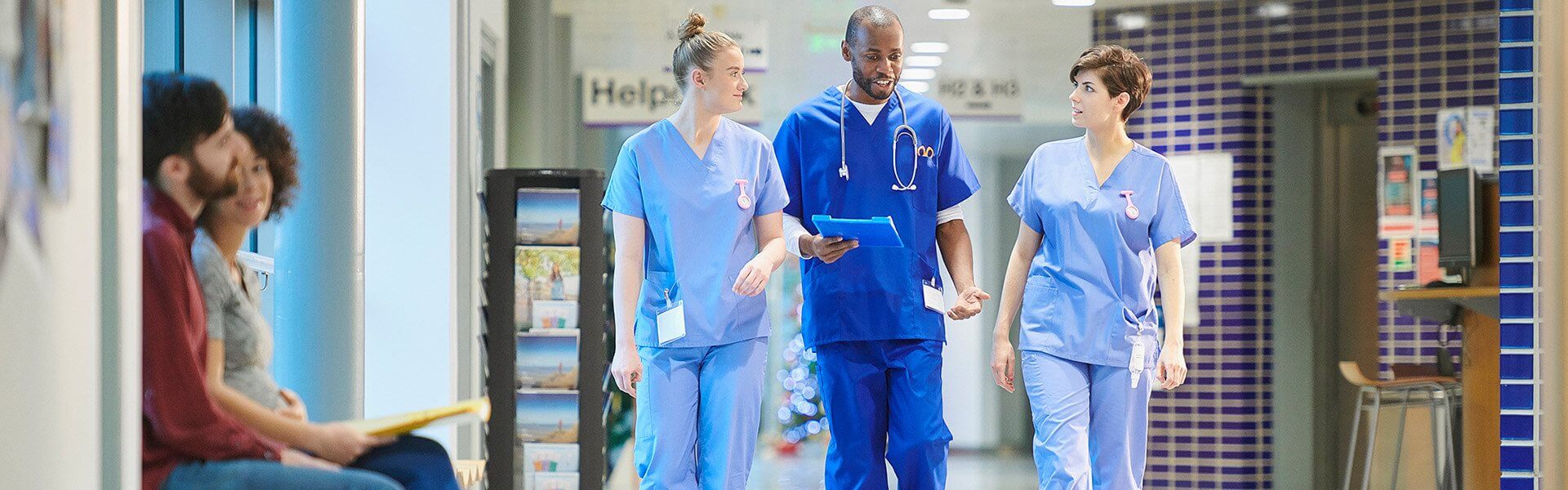 Two doctors in scrubs having a discussion as they walk through a hospital